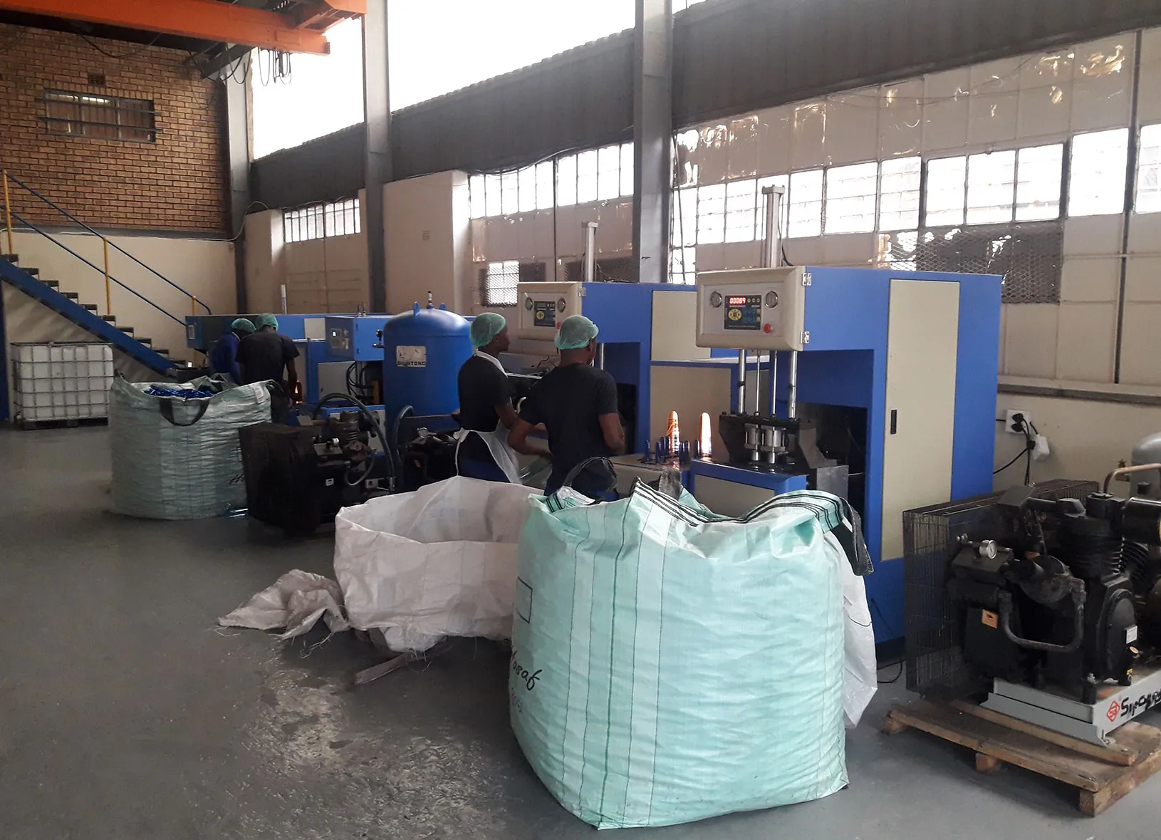 Inside the factory: blow moulding machines with bulk bags of PET material on the floor